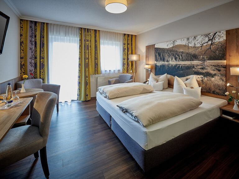 Das Doppelzimmer Sonnengarten ist schön dekoriert mit einem großen Landschaftsbild am Kopfende des Bettes