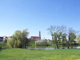 Der Blick über einen grünen Park mit See auf eine Kirche in Straubing.