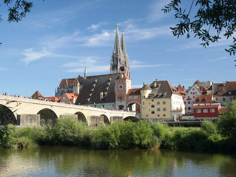 Eine malerische Steinbrücke überspannt den Fluss vor der Altstadt von Regensburg.